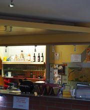 Verkaufstresen mit Speisen, Getränken und Landkarten an der Wand, darunter ein Sparschwein.