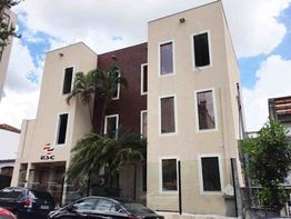 Prédio de três andares com palmeiras, carros estacionados em frente e logo ESC na fachada.