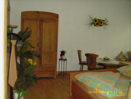 Gemütliches Schlafzimmer mit Holzmöbeln, Bett, Schrank, Pflanzen und Sonnenblumendekoration.