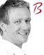 Mann lächelt, leicht zur Seite gedreht. Rotes "B" rechts oben.