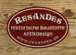Rotes Logo auf Holz mit Text: "RESANDES Historische Baustoffe Antikdesign www.resandes.de".