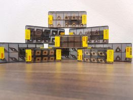 Kisten mit Metallteilen in Pyramidenform aufgestellt auf einem Holztisch.