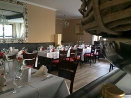 Elegantes Restaurant mit gedeckten Tischen, weißen Decken und roten Stühlen, bereit für Gäste.