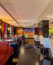 Restaurante elegante com mesas postas, cadeiras brancas e iluminação suave.