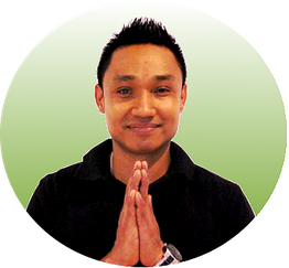 Mann mit schwarzem Shirt, lächelt und hält die Hände in Gebetshaltung vor grünem Hintergrund.