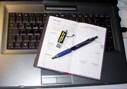 Ein Stift und ein Notizbuch liegen auf einer Laptop-Tastatur.