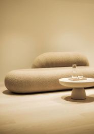 Minimalistisches Wohnzimmer mit modernem Sofa und kleinem Tisch auf hellem Holzboden.