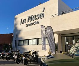 Edificio con letrero "La Masó Sports Club" y varias motos estacionadas al frente.