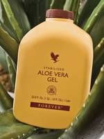 Gelbe Flasche Aloe Vera Gel vor grünen Blättern. Aufschrift: FOREVER.