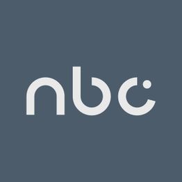 Logo grigio chiaro "nbc" su sfondo grigio scuro.