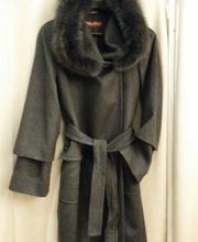 Dunkler Mantel mit Fellkragen und Gürtel, hängt an einem Kleiderbügel vor weißem Hintergrund.