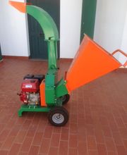 Trituratrice verde e arancione su ruote, posizionata su un pavimento di mattonelle rosse.