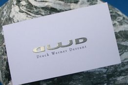 Weiße Karte auf einem Stein mit silberner Aufschrift "Druck Werner Durrant".
