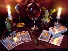Mesa con cartas de tarot, cristal, dos velas encendidas y un adorno de hada.