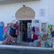 Negozio estivo con giochi da spiaggia e galleggianti appesi fuori, porta aperta.
