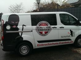Lieferwagen mit Werbung für Einbruchschutz, Abbildung einer maskierten Person, Webseite unten.