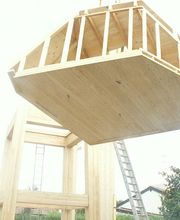 Holzrahmenstruktur wird mit einem Kran angehoben, in einem Wohngebiet im Freien.