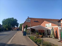 Landstraße mit Lokal, Schild "Spargel," blauer Himmel, Bäume im Hintergrund, keine Menschen.