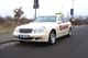 Beiges Taxi, Mercedes-Benz, steht am Straßenrand auf einem Parkplatz.