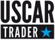 Schwarzer Text "USCAR" über "TRADER" mit blauem Stern rechts unten auf weißem Hintergrund.