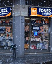 Negozio di cartucce e toner durante una nevicata. Vetrine piene di offerte e prodotti in mostra.