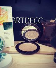 Productos de maquillaje Artdeco sobre una mesa: bronceador, brocha, cápsulas y crema.