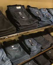 Gefaltete Jeans in verschiedenen Farben auf zwei Regalböden in einem Geschäft.