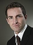 Ein Mann im Anzug vor grauem Hintergrund.