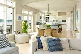 Bright open living area with cozy seating, dining set, and kitchen, overlooking large windows.