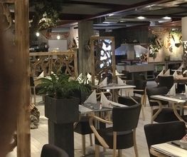 Ein stilvoll eingerichtetes Restaurant mit Holzdekor und gedeckten Tischen in gemütlicher Atmosphäre.