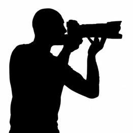 Scherenschnitt eines Fotografen, der eine Kamera mit großem Objektiv hält.