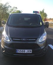 Taxi negro con matrícula 5568 JXN estacionado en una carretera rural bajo un cielo despejado.