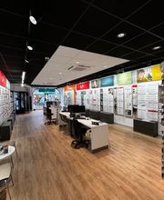 Optiekwinkel interieur met brillenrekken en tafels op houten vloer.