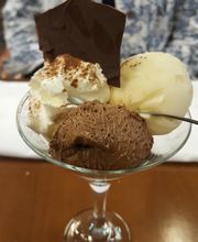 Postre en copa con helado de vainilla, chocolate, nata y decoración de chocolate oscuro.