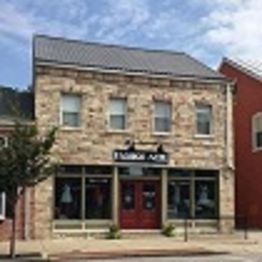 Stone building labeled "Embroid Me" under a blue sky.