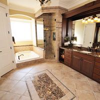 Luxurious bathroom with a soaking tub, glass shower, and dark wood vanity under warm lighting.