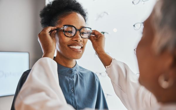 Optikerin passt einer Kundin eine Brille passend zu ihrer Gesichtsform an.