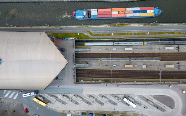 Luftaufnahme eines beladenen Containerschiffes mit angrenzenden Bahnhof.