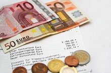 Zwei Euro-Scheine, mehrere Münzen und ein Kontoauszug auf einer weißen Oberfläche.