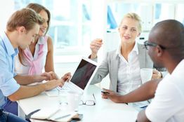 Group of four people having a meeting, using a laptop and taking notes.