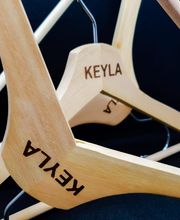 Perchas de madera con la inscripción "KEYLA" en un fondo negro.