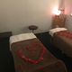 Spa room with two massage tables covered in brown sheets and rose petals arranged in a heart shape.