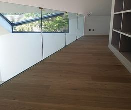 Holzboden, Glasgeländer, rechtwinklige Architektur in modernem Raum, Sonnenlicht durch Fenster.