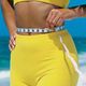 Donna in abbigliamento giallo misura la vita con un metro su una spiaggia.