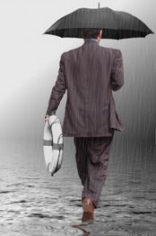 Person im Anzug mit Regenschirm und Rettungsring geht durch Regen.