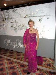 Eine Person in einem pinken Kleid steht vor einer Wand mit der Aufschrift "Harry's Bar".