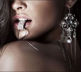 Mujer con pendientes grandes y cadena en labios, primeros planos de rostro y hombro.