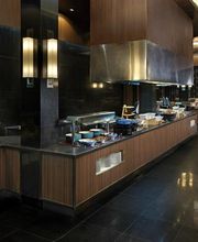 Cocina elegante con encimeras de madera y fruta a la vista en un ambiente moderno y oscuro.
