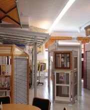 Ein Ausstellungsraum mit Markisen, Fenstermodellen und Möbeln, hell beleuchtet.