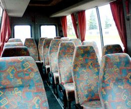 Leerer Businnenraum mit bunt gemusterten Sitzen und roten Vorhängen an den Fenstern.